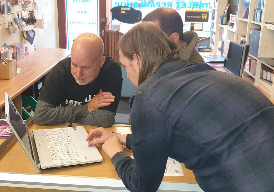 Craig explaining a laptop issue to customers at the Volts UK shop counter